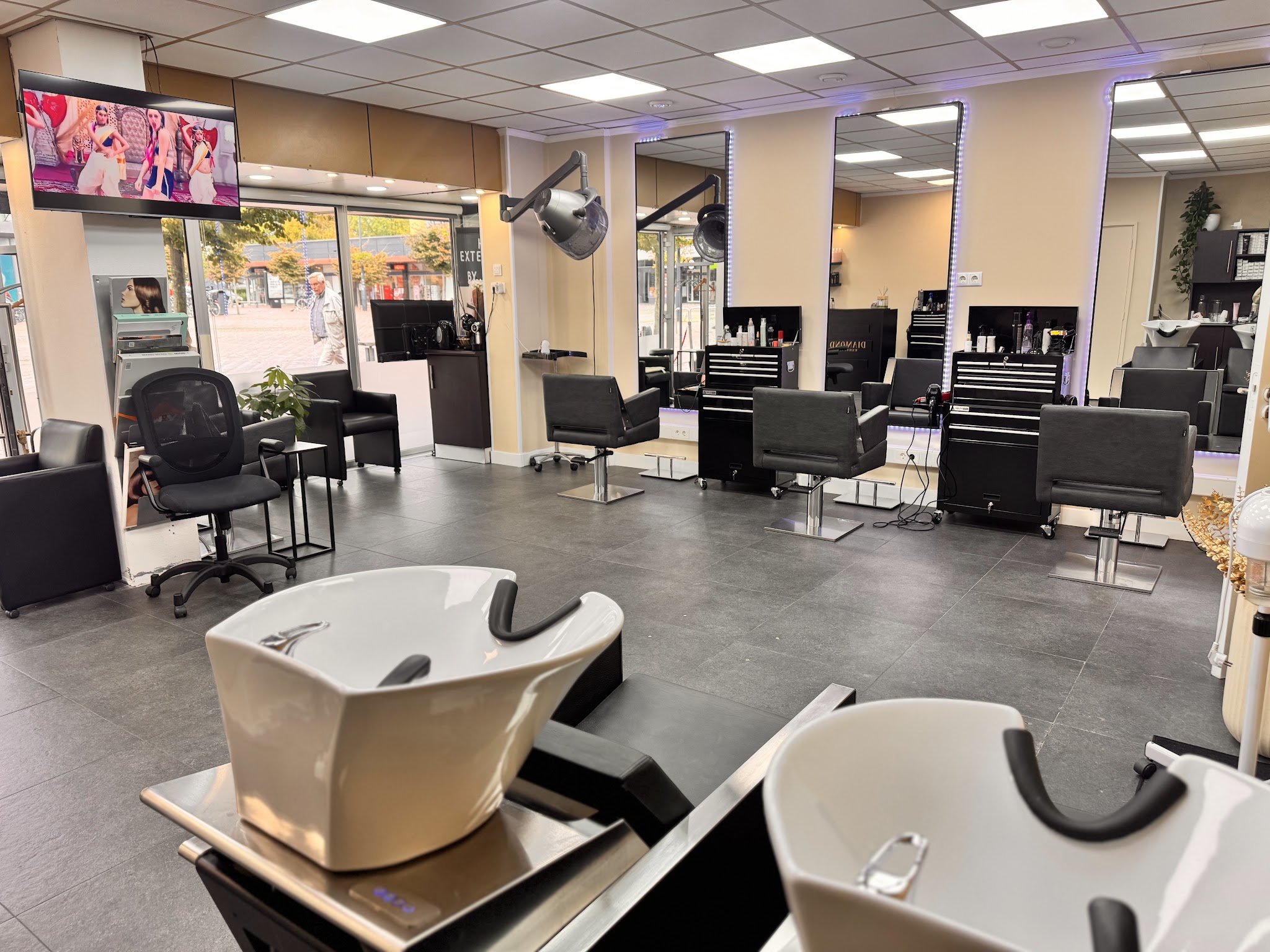 De salon: twee wasplaatsen vooraan, daarachter een rij kappersstoelen voor de spiegels